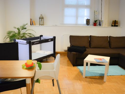 Wohn-/ Esszimmer geräumiges Wohnzimmer mit Babybett und Kinderhochstuhl